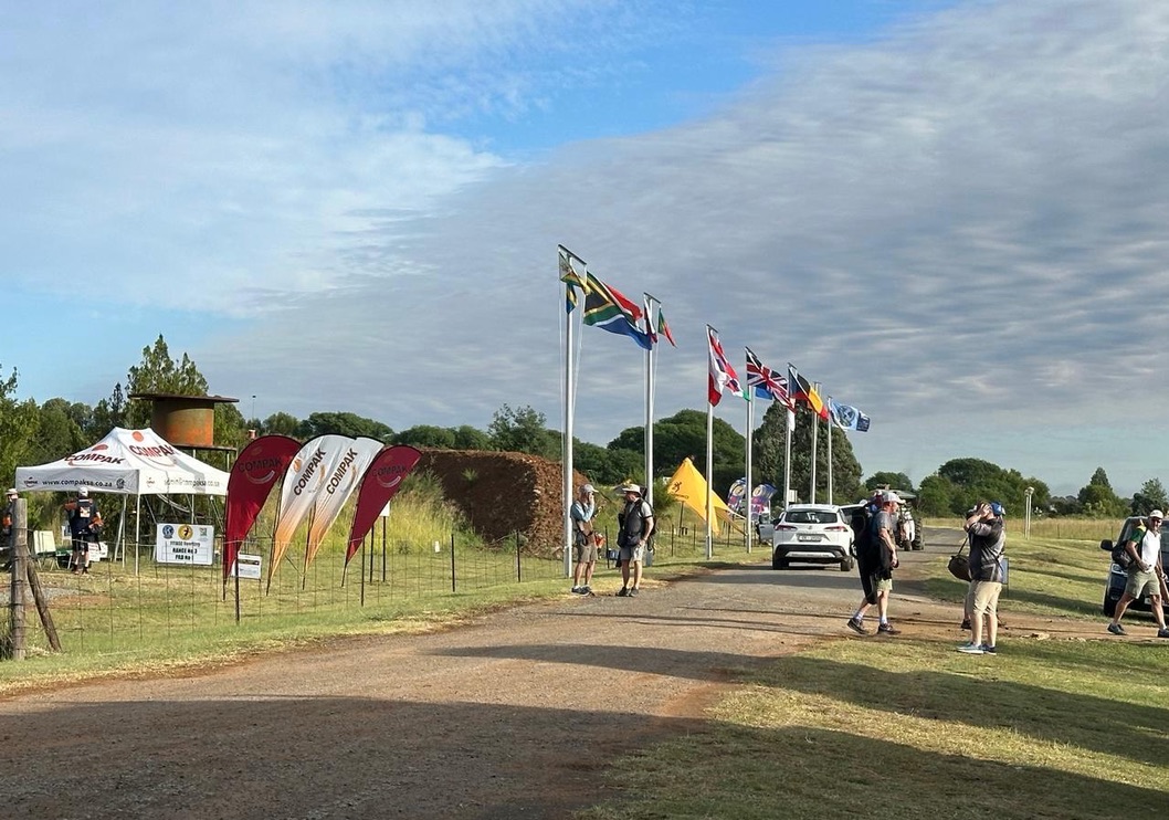 Compak flags and international flagpoles line the Maccauw entrance road